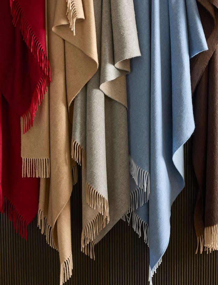 A view of several Paley throws hanging along a wall