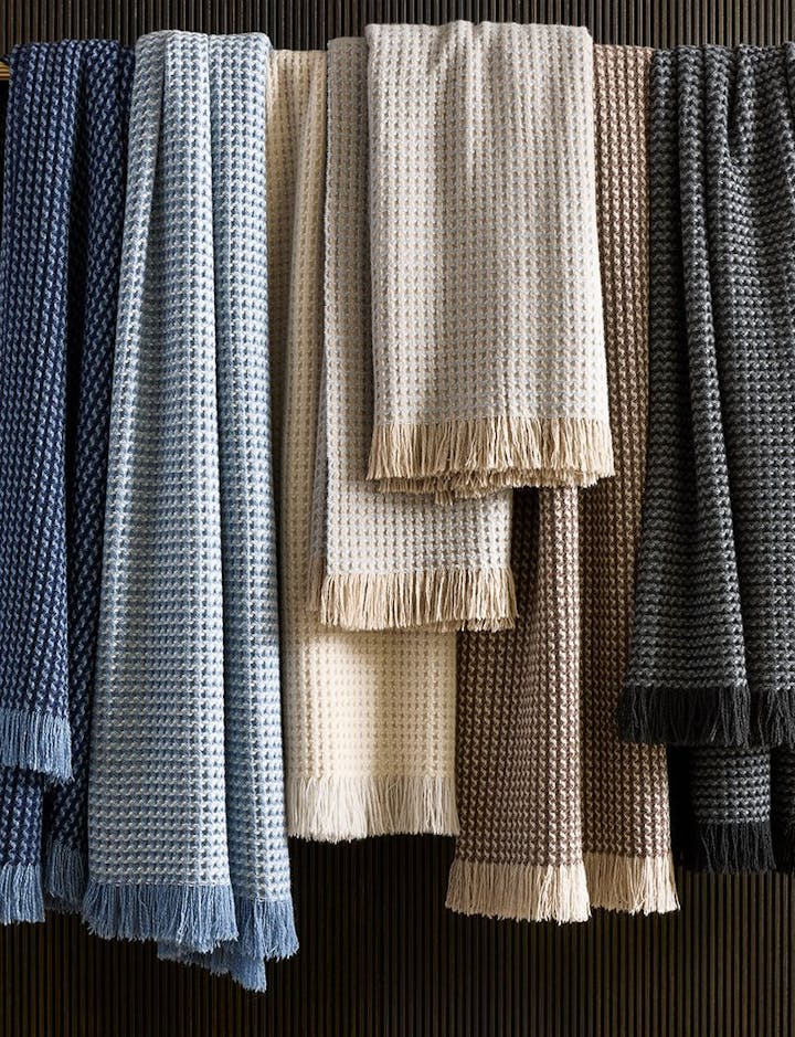 A view of several Cleo throws hanging in front of a wall.