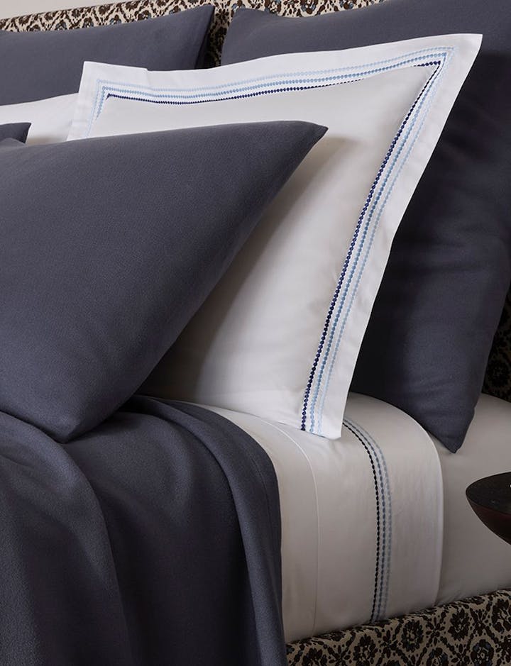 A bed with Amara Triple Pearl bed linens, along with a Dream Modal blanket.